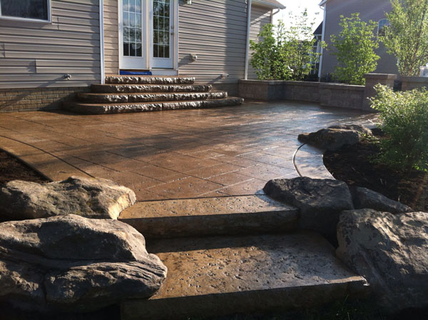 Brown Travertine Stamped Concrete Patio with Rock Inlays